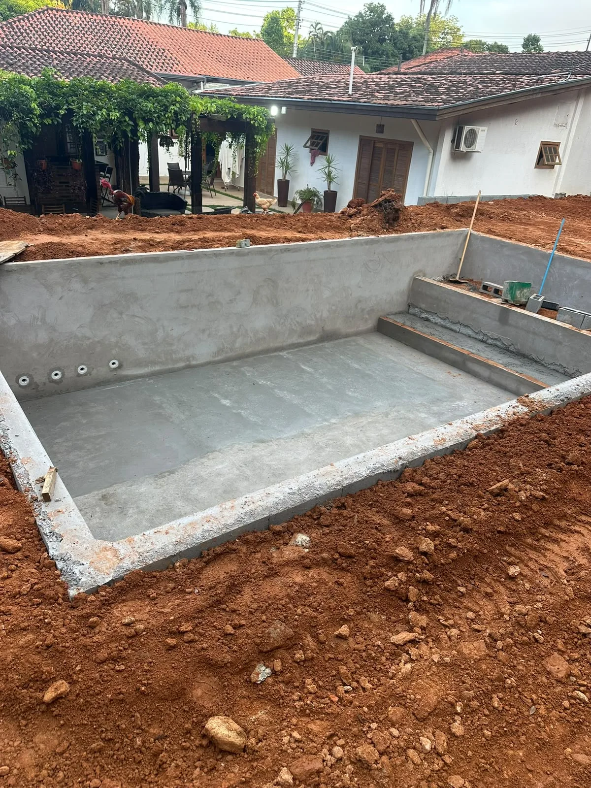 Piscina em construção com casa de máquinas e instalações sendo preparadas